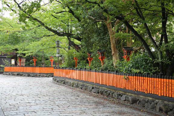石畳と緑、朱色の名札が鮮やかな祇園の風景